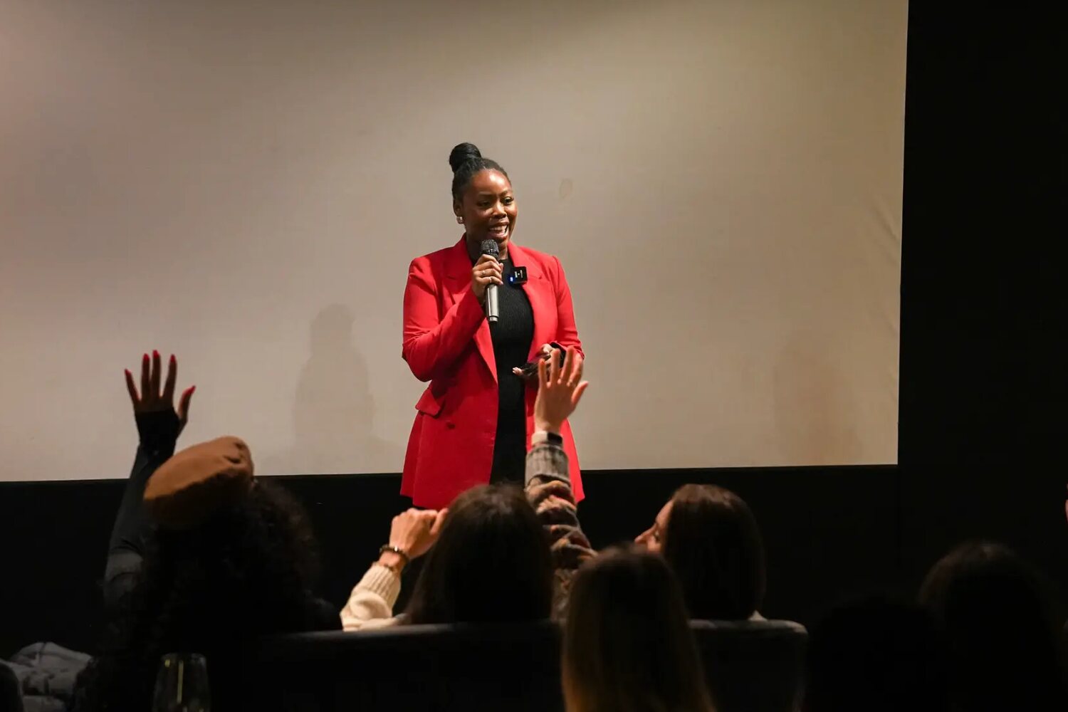 A founder speaking live on stage in front of an audience with hands raised